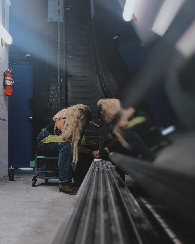 Kay and a team member working beside a vehicle in the shop