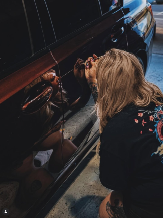 Kay completing precise exterior work on a dark vehicle